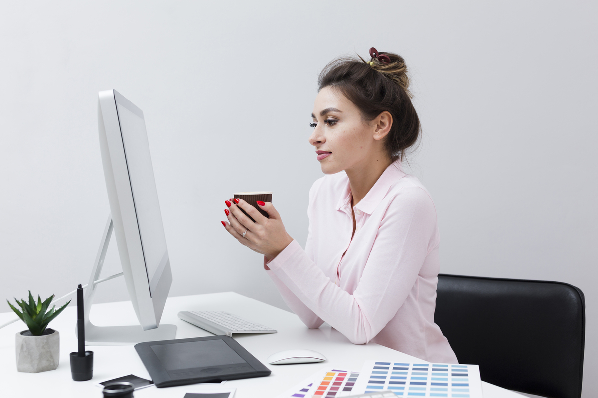 mulher com celular nas maos sentada em frente ao computador
