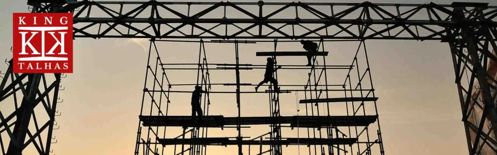 Operários trabalhando em andaime ao entardecer.
