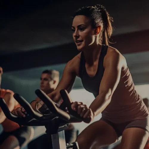 Pessoas praticando spinning em academia iluminada